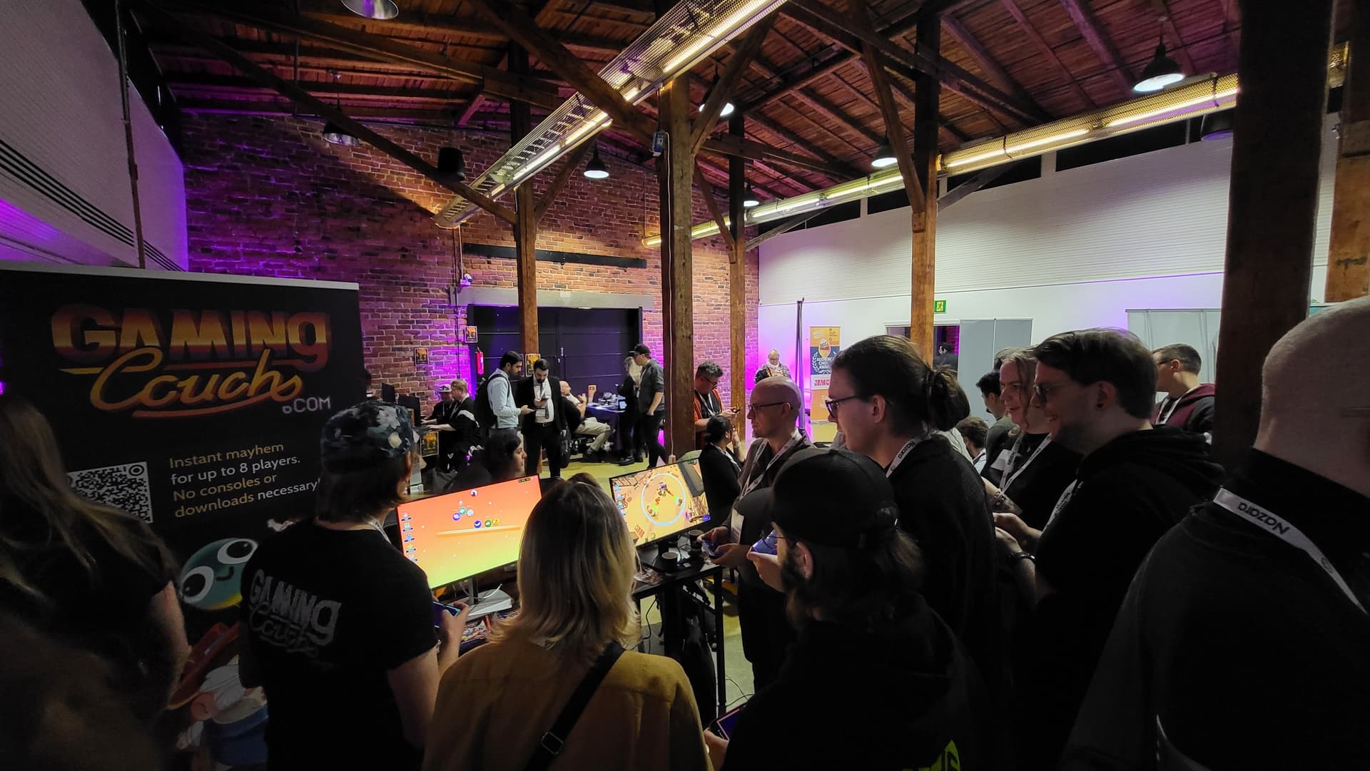 A crowd gathered around the Gaming Couch booth playing party games at Pocket Gamer Connects Helsinki